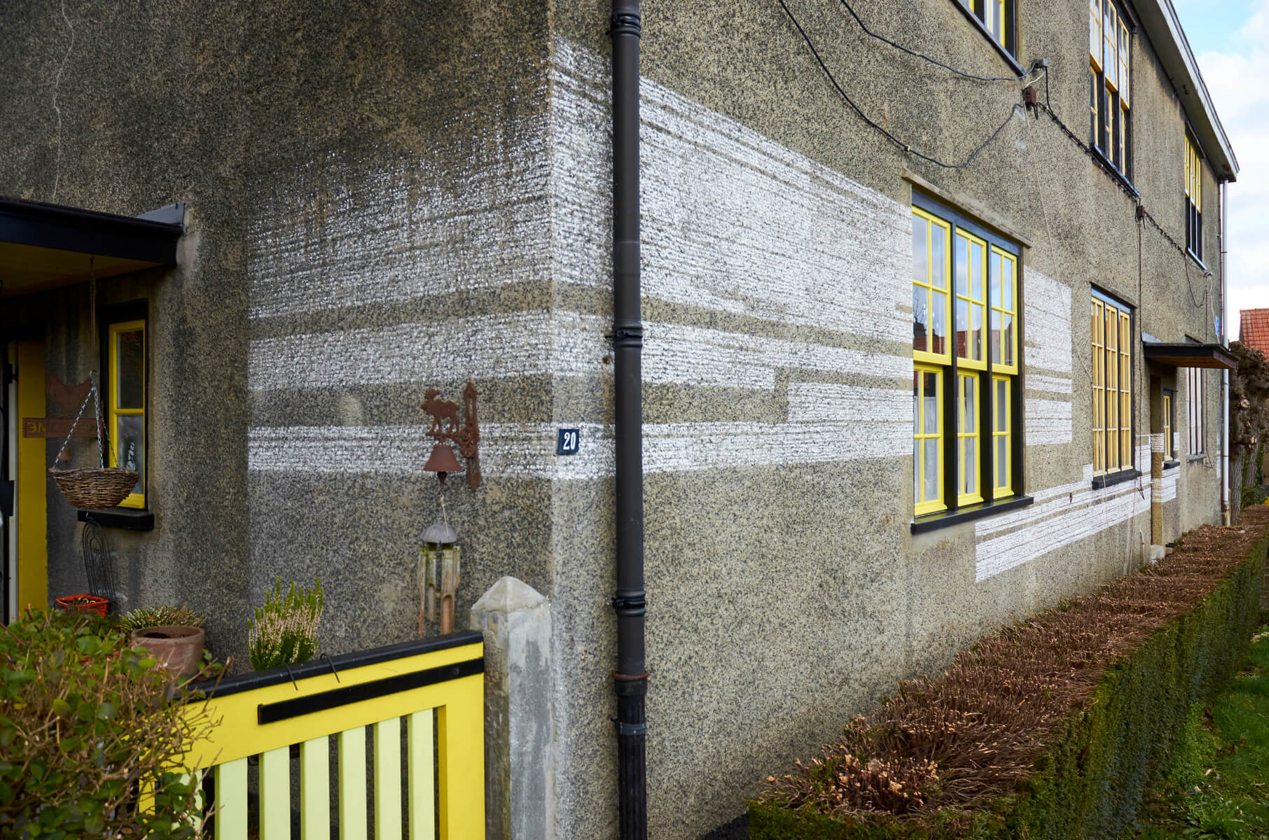 Chalk linedrawing on the corner of a house with green and yellow windows