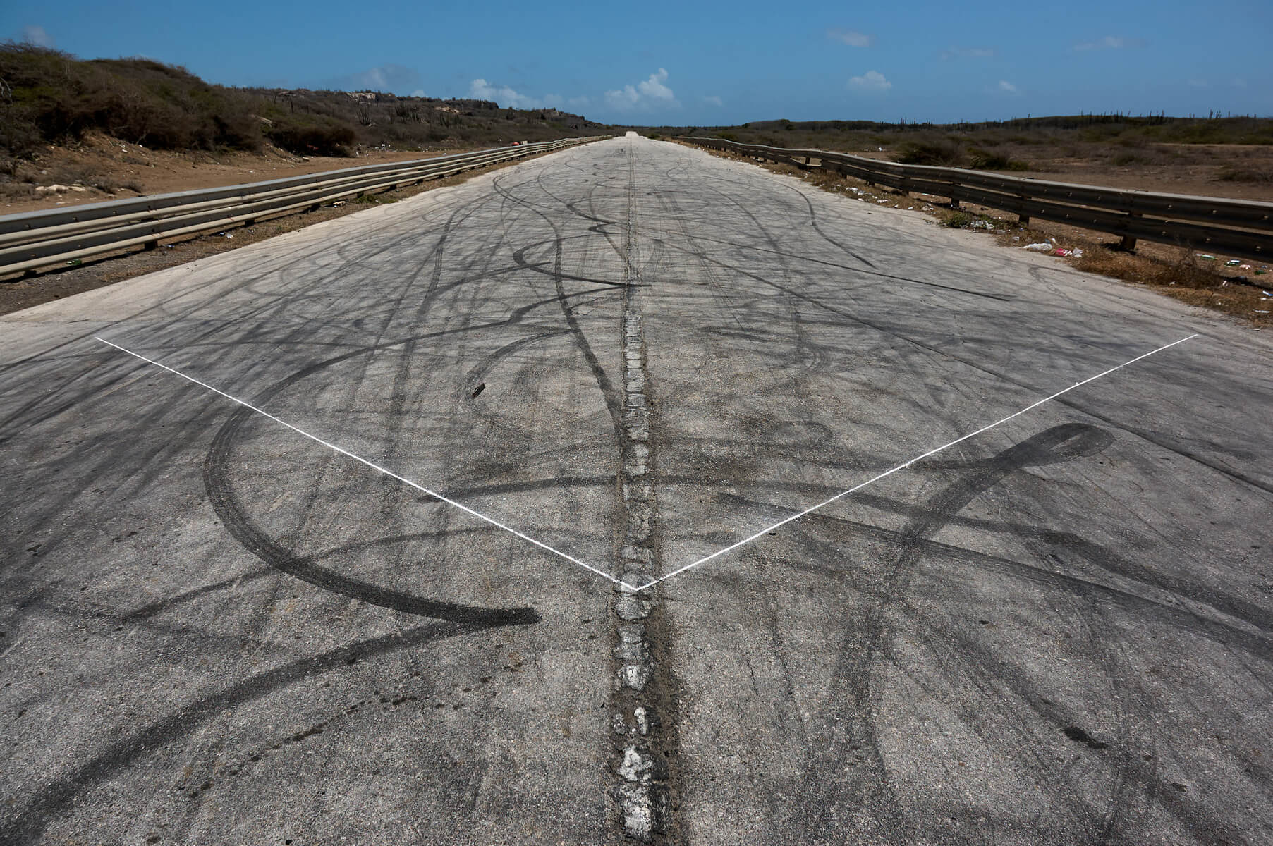 Chalk linedrawing on an road with no cars yet with many skid marks